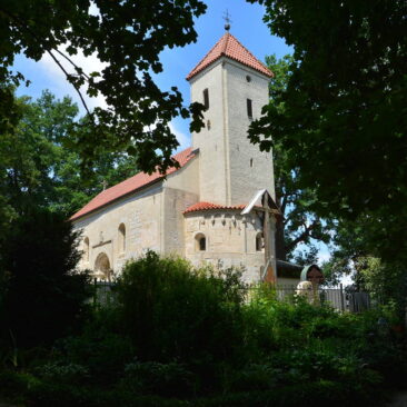 Kleine Kirche aus Sandstein umrahmt von Blättern