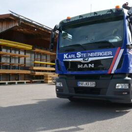 Blauer Lastwagen mit weißem Schriftzug Karl Steinberger. Im Hintergrund Ausschnitt des Werksgeländes zu sehen